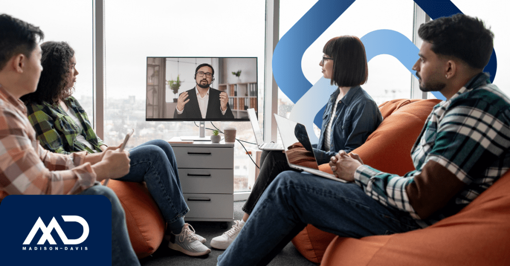 Employees in dressed-down attire attend a meeting with a manager speaking from a screen